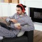homem de pijamas longos sentado no sofá comendo pipoca
