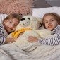 duas meninas deitadas na cama abracando um urso de pelucia