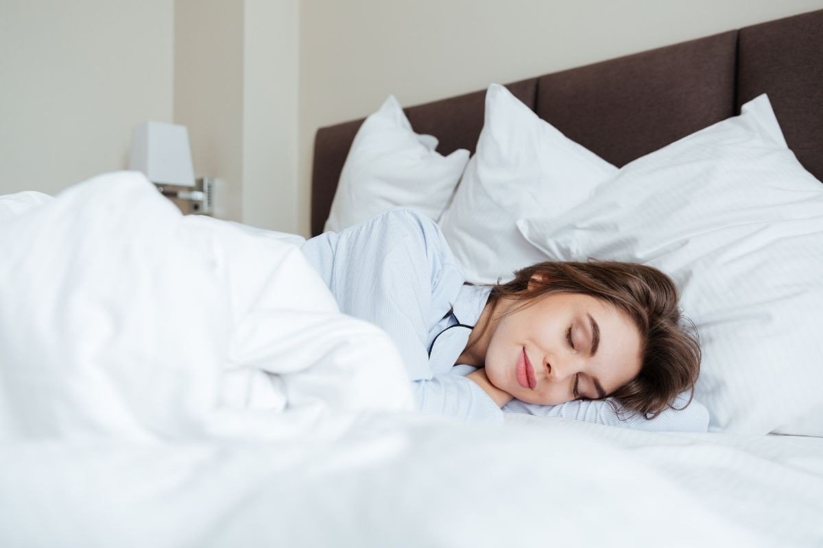 mulher dormindo em cama com lençol branco